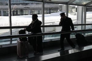 A passenger and a member of a flight crew walk through Toronto's Pearson Airport as snow piles up around the area during heavy snowfall on Monday, Jan. 26, 2026. THE CANADIAN PRESS/Chris Young